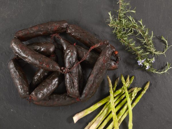 Morcilla Ristra de morcillas con verdura a forma de adorno estético sobre un fondo negro.